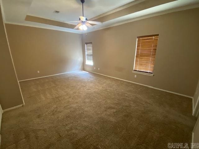 unfurnished room featuring ceiling fan, a raised ceiling, crown molding, baseboards, and carpet floors