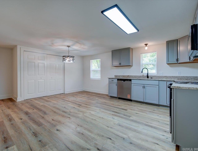 kitchen with baseboards, stainless steel dishwasher, light wood-style flooring, a sink, and gray cabinetry