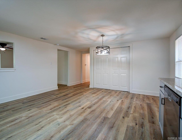 unfurnished dining area with a notable chandelier, visible vents, light wood-style flooring, and baseboards