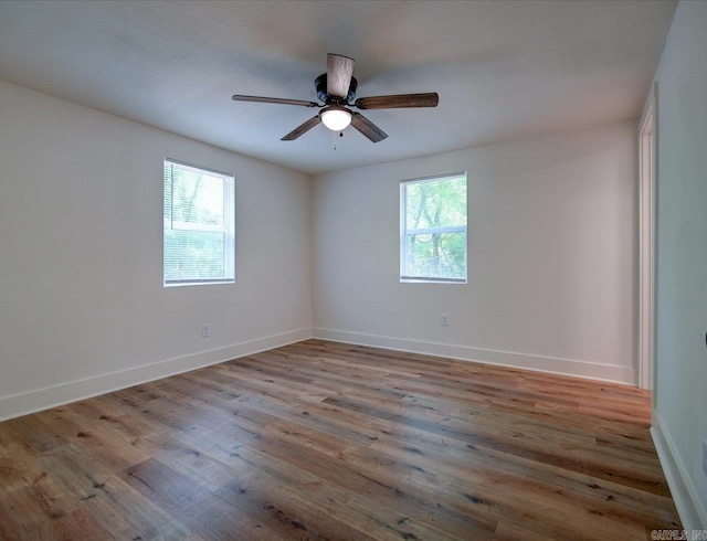 unfurnished room featuring a ceiling fan, wood finished floors, and baseboards