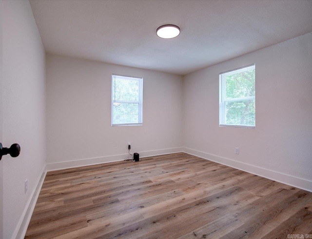 spare room featuring baseboards, light wood-style floors, and plenty of natural light