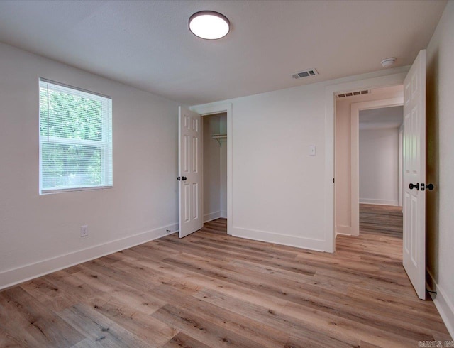 unfurnished bedroom with visible vents, a closet, light wood finished floors, and baseboards