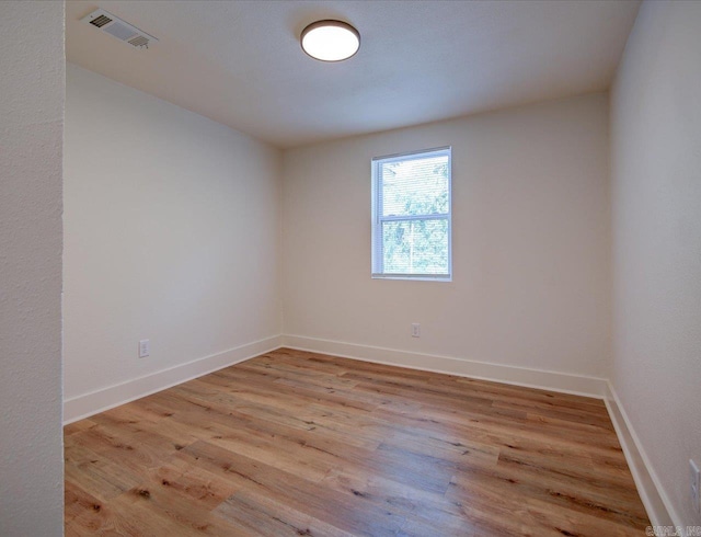 spare room featuring baseboards, visible vents, and light wood-style flooring