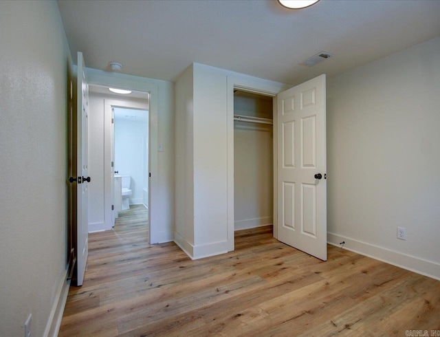 unfurnished bedroom featuring baseboards, visible vents, light wood-style floors, and a closet