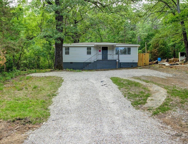 manufactured / mobile home with driveway, crawl space, and a forest view
