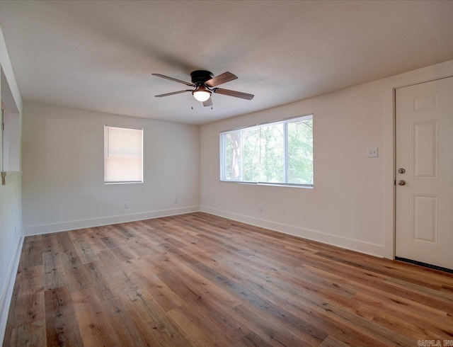 unfurnished room featuring wood finished floors, a ceiling fan, and baseboards
