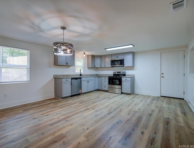 kitchen featuring gray cabinets, light wood-style flooring, stainless steel appliances, and visible vents
