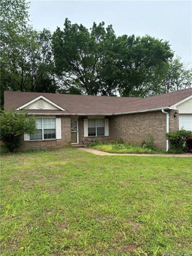 single story home featuring brick siding, a front lawn, and an attached garage