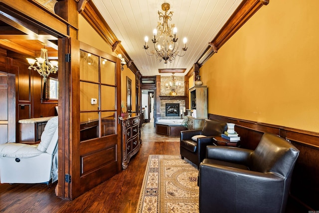 living area with a chandelier, wooden ceiling, dark wood-style flooring, ornamental molding, and a fireplace