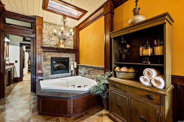 full bathroom with a skylight, wood ceiling, stone finish flooring, a notable chandelier, and a jetted tub