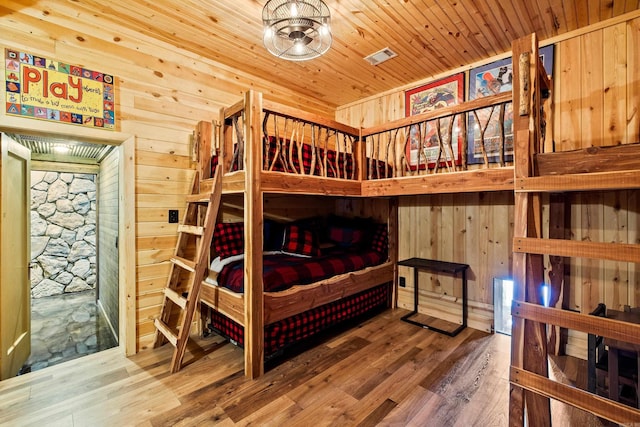 bedroom with wooden ceiling, wood walls, wood finished floors, and visible vents