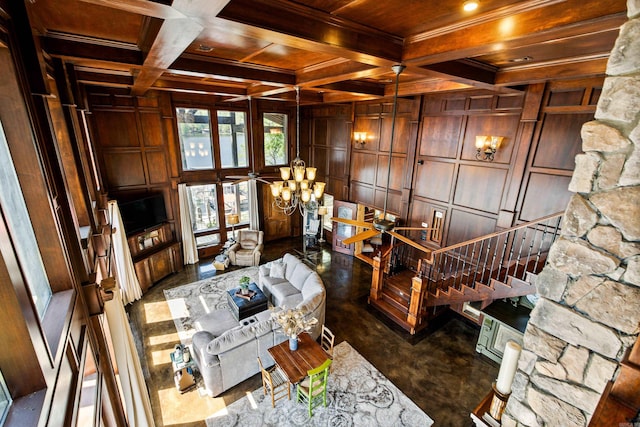 living area with wood ceiling, beamed ceiling, coffered ceiling, stairs, and ceiling fan with notable chandelier