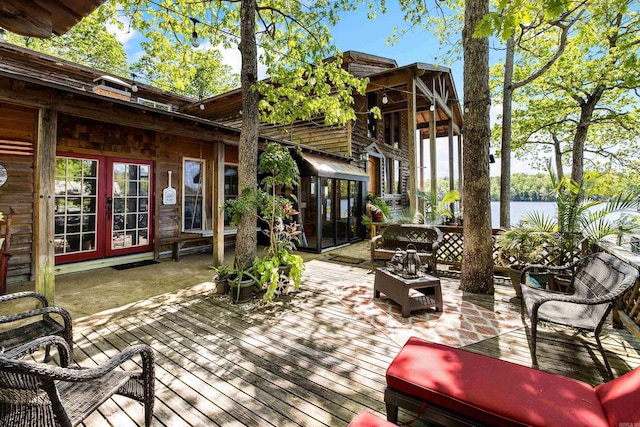 wooden terrace with a water view, french doors, an outdoor hangout area, and a sunroom