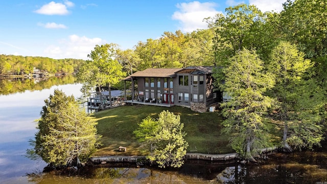 exterior space featuring a lawn, a water view, and a forest view