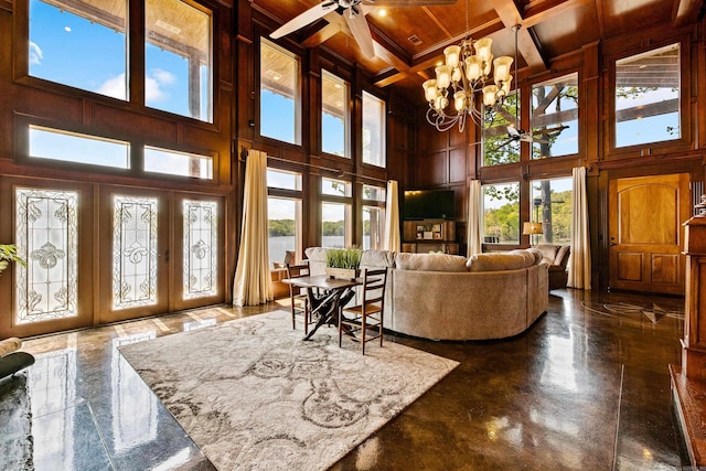 living room with beamed ceiling, coffered ceiling, wooden ceiling, a towering ceiling, and ceiling fan with notable chandelier