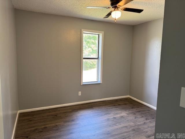 unfurnished room with a textured ceiling, ceiling fan, wood finished floors, and baseboards