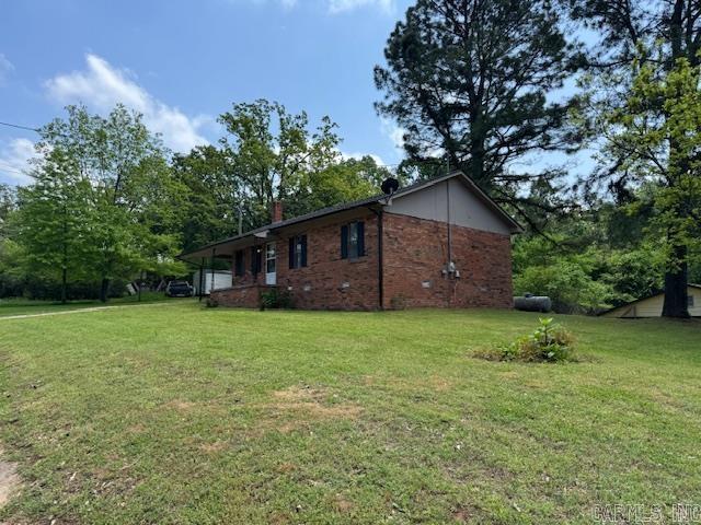 view of home's exterior with a chimney, a yard, and brick siding