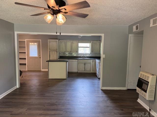 kitchen with a textured ceiling, heating unit, stainless steel dishwasher, and a sink