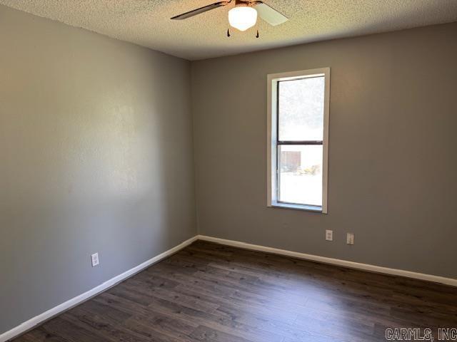 unfurnished room featuring a textured ceiling, dark wood-style flooring, ceiling fan, and baseboards