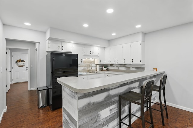 kitchen featuring freestanding refrigerator, a peninsula, baseboards, dark wood-type flooring, and light countertops