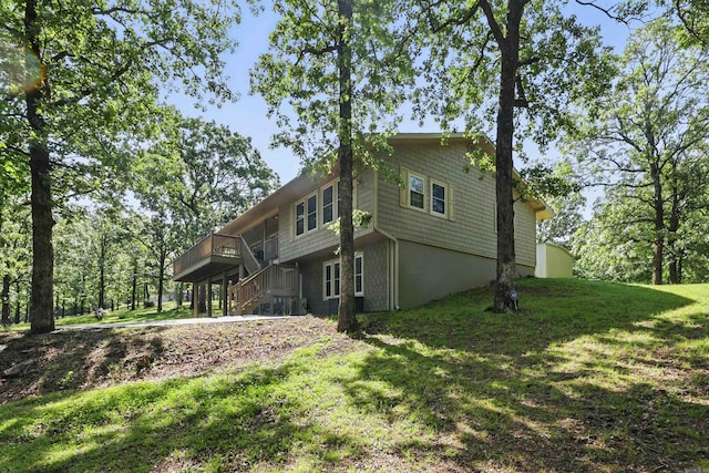 view of side of property featuring stairway, a lawn, and a deck