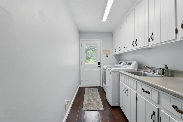 washroom featuring dark wood-style flooring, baseboards, washer and clothes dryer, a sink, and cabinet space