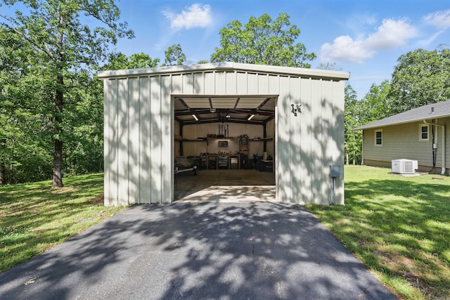 view of outbuilding with aphalt driveway, central air condition unit, and an outbuilding