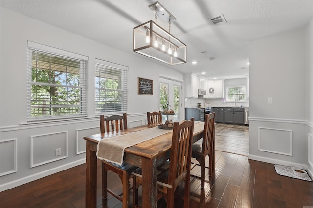 dining area with dark wood-style flooring, visible vents, recessed lighting, and a wainscoted wall