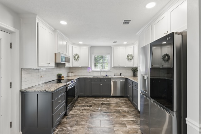 kitchen featuring a sink, gray cabinets, stainless steel appliances, and white cabinetry