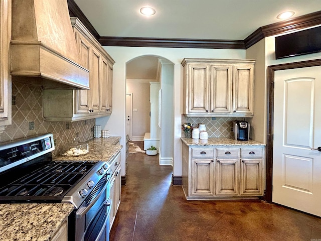 kitchen featuring ornamental molding, baseboards, tasteful backsplash, stainless steel range with gas stovetop, and arched walkways