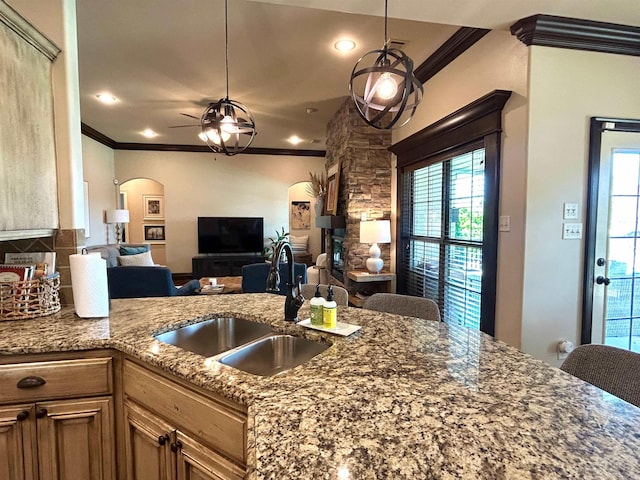 kitchen featuring a sink, arched walkways, ornamental molding, and dark stone counters