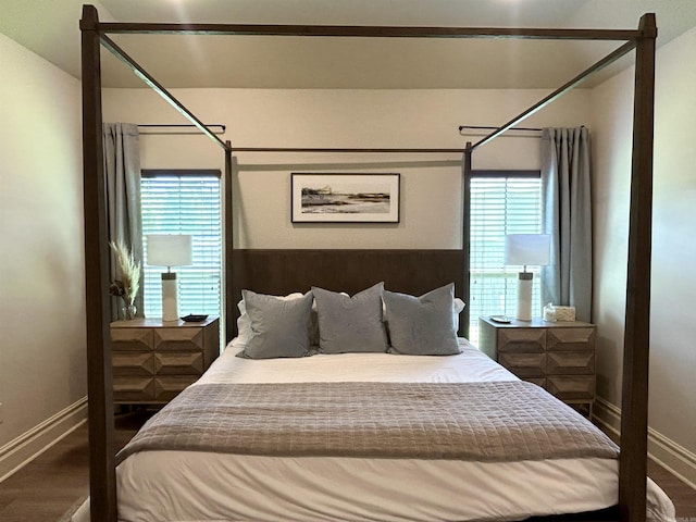 bedroom featuring baseboards, multiple windows, and wood finished floors