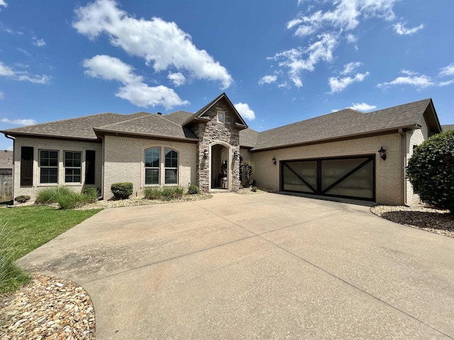 view of front of home featuring a front lawn, roof with shingles, brick siding, an attached garage, and driveway