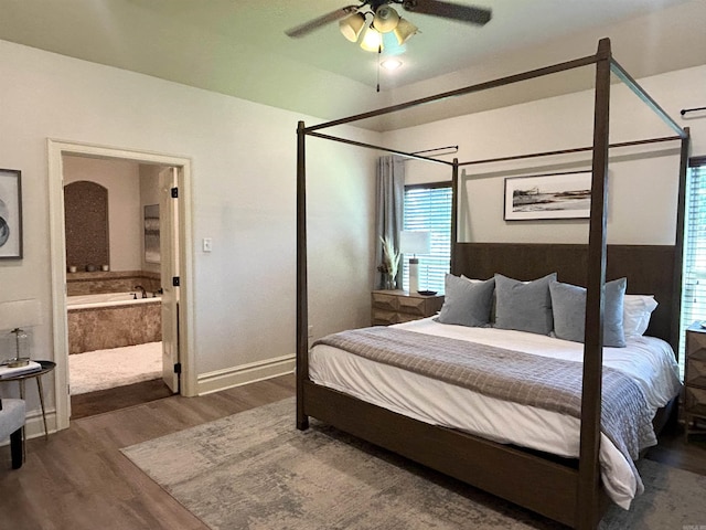bedroom with baseboards, ceiling fan, wood finished floors, and connected bathroom