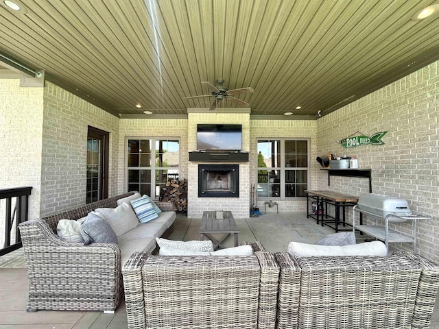 view of patio featuring a ceiling fan, an outdoor living space with a fireplace, and area for grilling