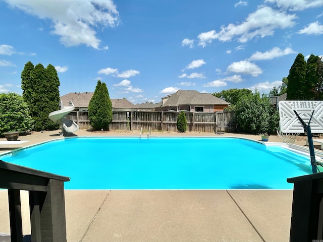 view of swimming pool with a patio, a water slide, a fenced backyard, and a fenced in pool