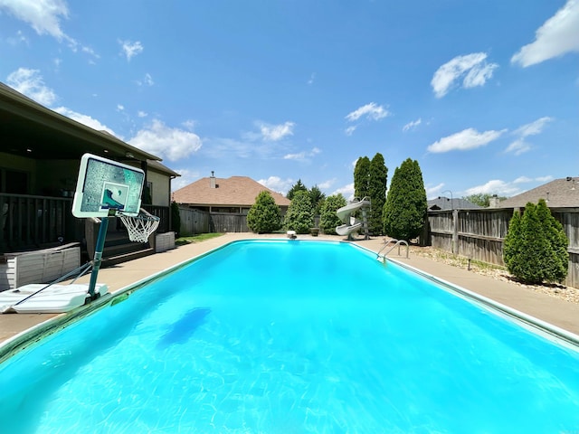 view of pool featuring a fenced backyard, a fenced in pool, a water slide, and a diving board