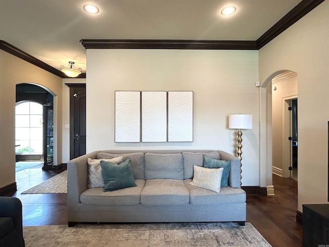 living area featuring crown molding, arched walkways, wood finished floors, baseboards, and recessed lighting
