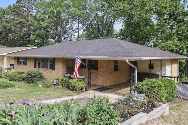 single story home featuring brick siding, a carport, driveway, and roof with shingles