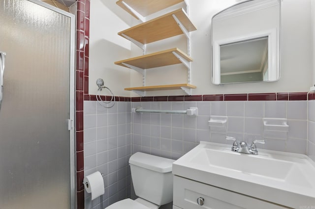 full bath with tile walls, vanity, toilet, a stall shower, and a wainscoted wall