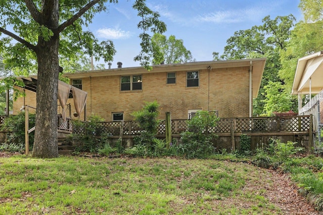 back of property with fence, a lawn, and brick siding