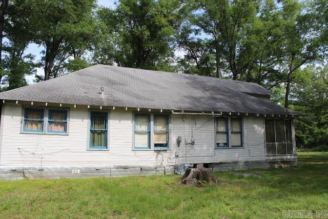 back of house featuring a lawn, roof with shingles, and a sunroom
