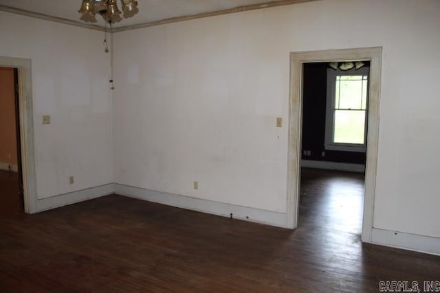 spare room featuring baseboards, crown molding, and dark wood-type flooring