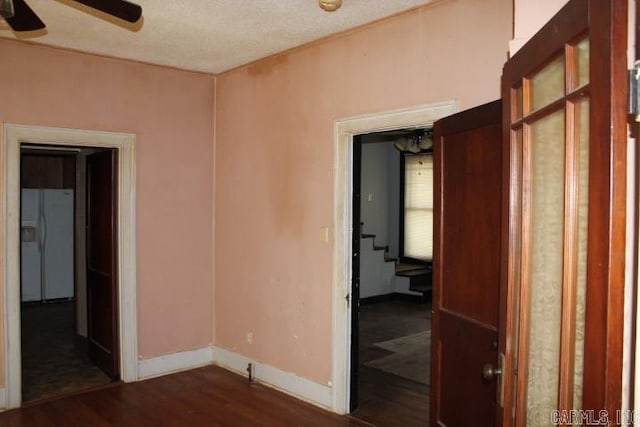 spare room with baseboards, wood finished floors, and a ceiling fan