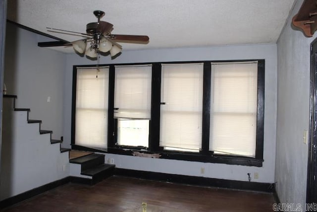 spare room with stairway, ceiling fan, a healthy amount of sunlight, and wood finished floors
