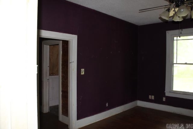 spare room with baseboards, ceiling fan, and dark wood-type flooring