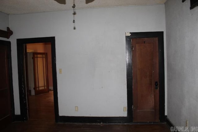 spare room with ceiling fan, baseboards, and dark wood-type flooring