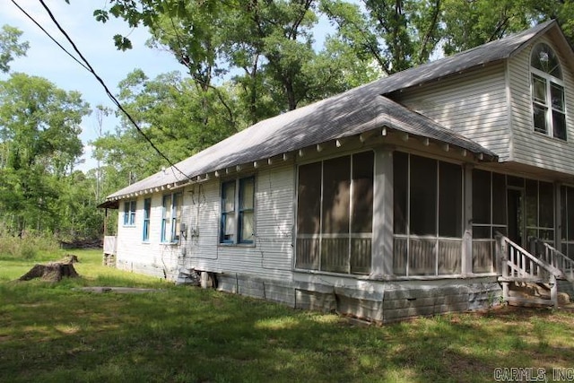 view of home's exterior featuring a sunroom and a lawn