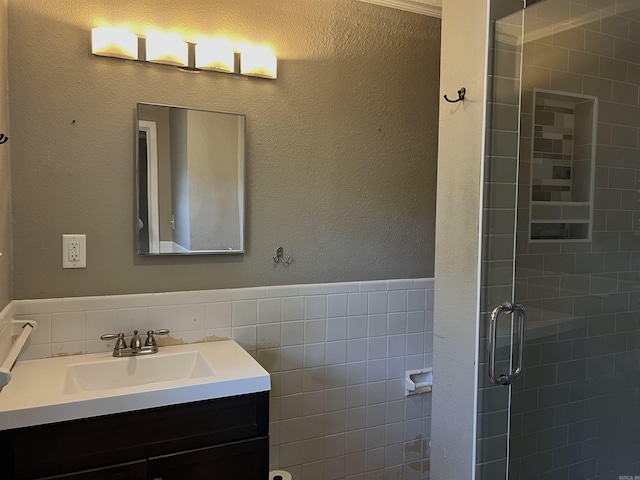 bathroom featuring a stall shower, tile walls, a wainscoted wall, and vanity
