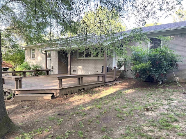 rear view of property featuring a wooden deck and brick siding